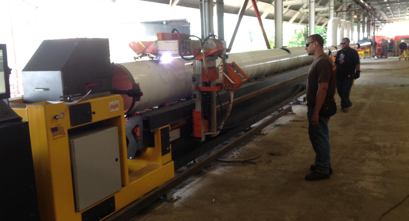 Workers welding piping in warehouse